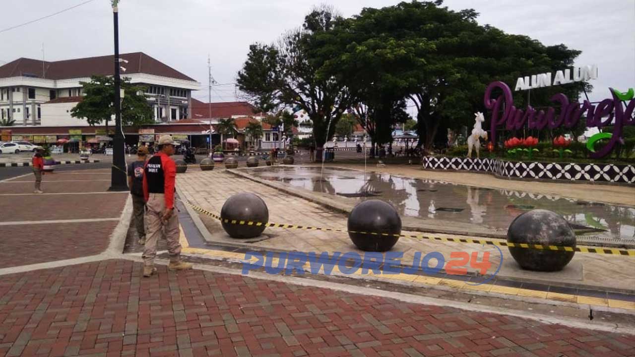 Satpol PP memasang pita kuning sebagai penanda larangan melitnas di sejumlah fasilitas umum di Alun-alun Purworejo