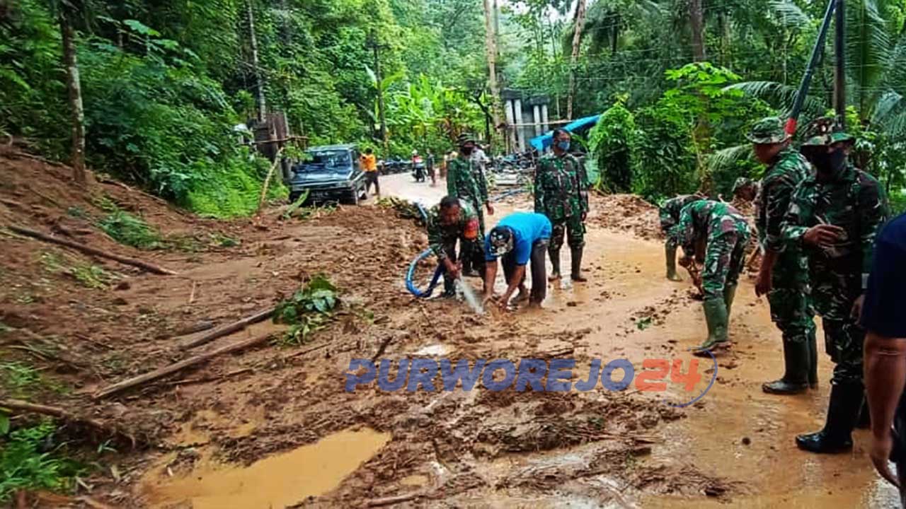 Warga bersama anggota TNI membersihkan material longsor yang menutup jalan.