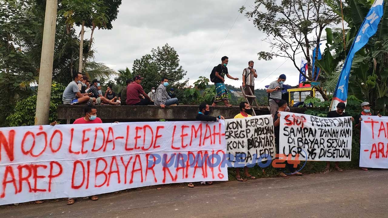 Puluhan warga membentangkan spanduk di jalan masuk proyek Bendungan Bener di Dusun Kalipancer.