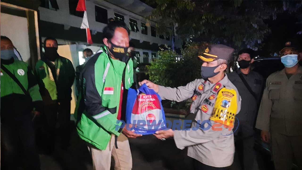 Kapolres Purworejo menyerahkan paket sembako kepada pengojek daring.