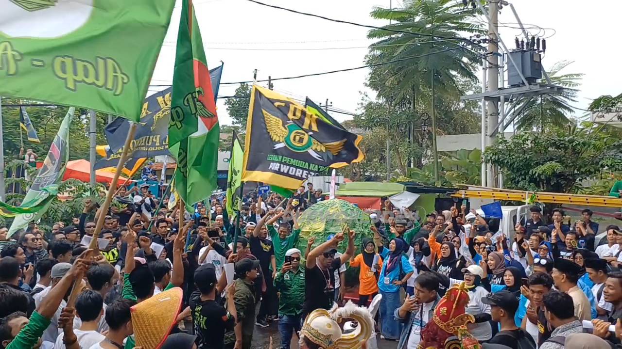 Masa pendukung Paslon nomor 1 membawa replika jeruk dan uang raksasa di lokasi halaman debat paslon, pada Senin (18/11/2024)