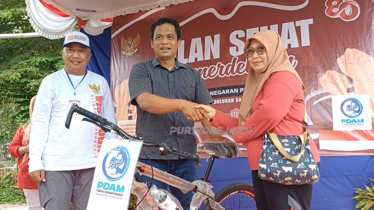 Ketua RW 10 Suronegaran bersama perwakilan PDAM Tirta Perwitasari saat menyerahkan hadiah utama berupa sepeda kepada peserta jalan sehat yang beruntung